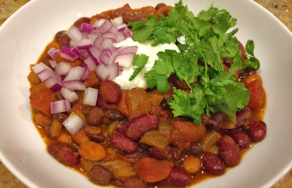 Meatless chili with 3 beans topped with cilantro, sour cream, and red onions.