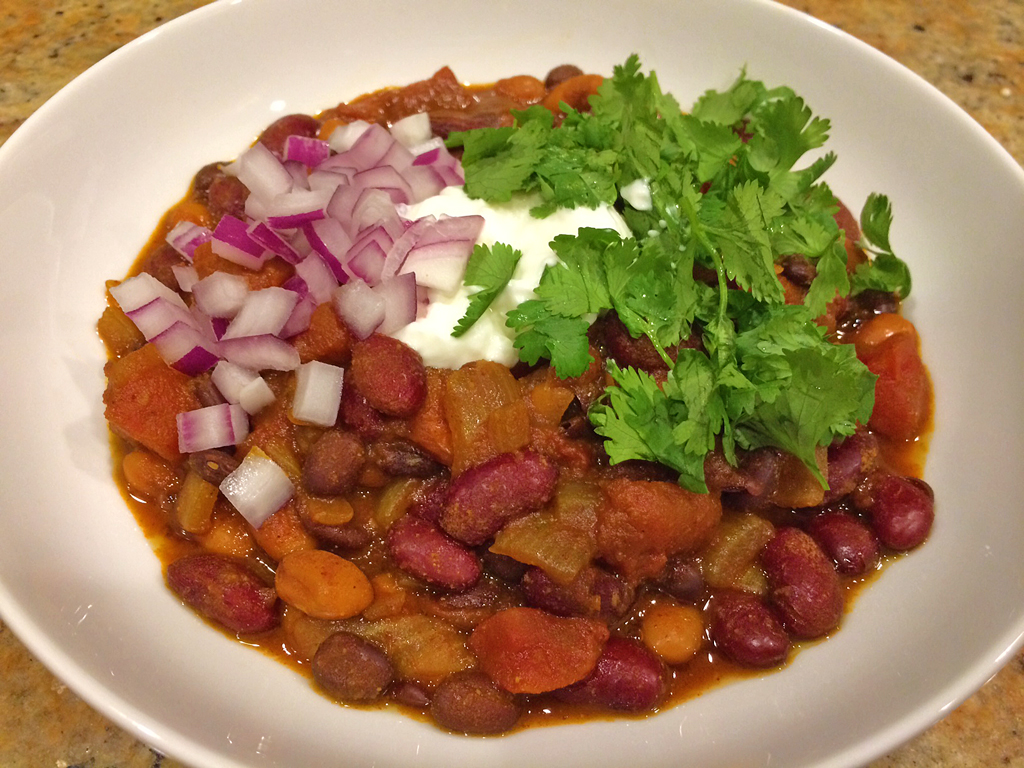 Meatless chili with 3 beans topped with cilantro, sour cream, and red onions.