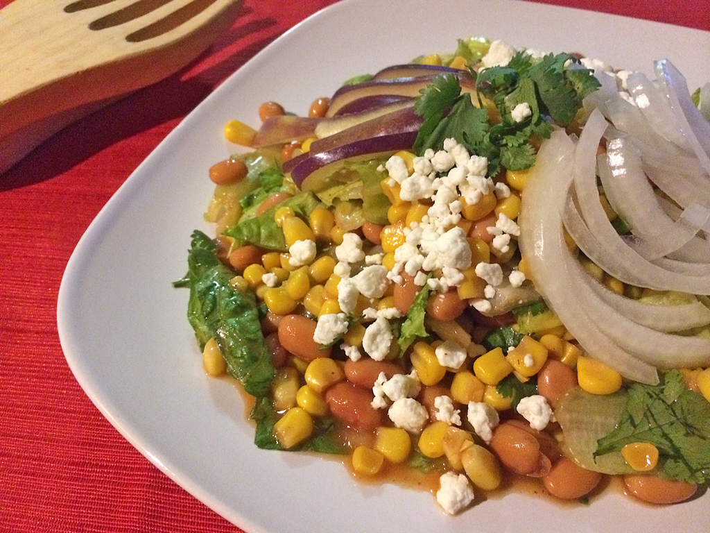 Meatless dinner salad with lettuce, pinto beans, red onions, and corn.