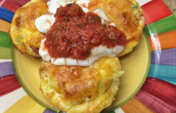 Baked Eggs in Muffin Tin topped with cheese, salsa, and sour cream.