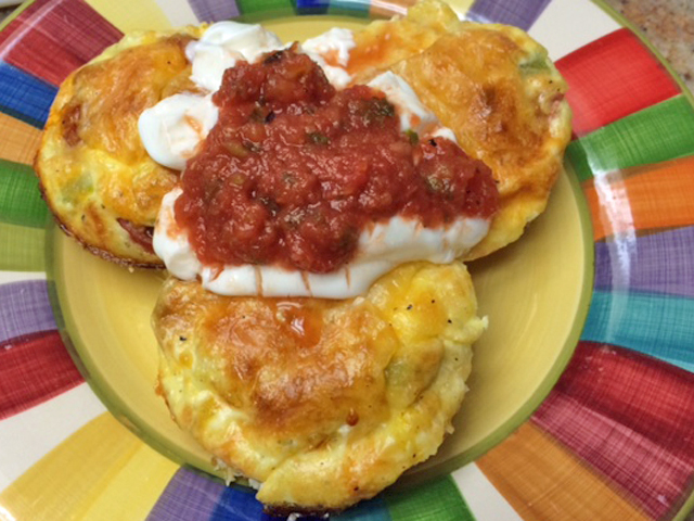 Baked Eggs in Muffin Tin topped with cheese, salsa, and sour cream.