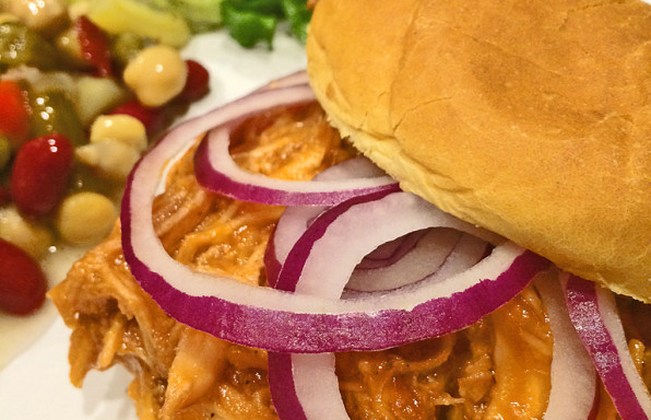 Barbecue Chicken Sandwich on hamburger bun with red onions.