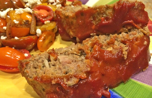 Slices of easy healthy meatloaf with ketchup and tomato salad.