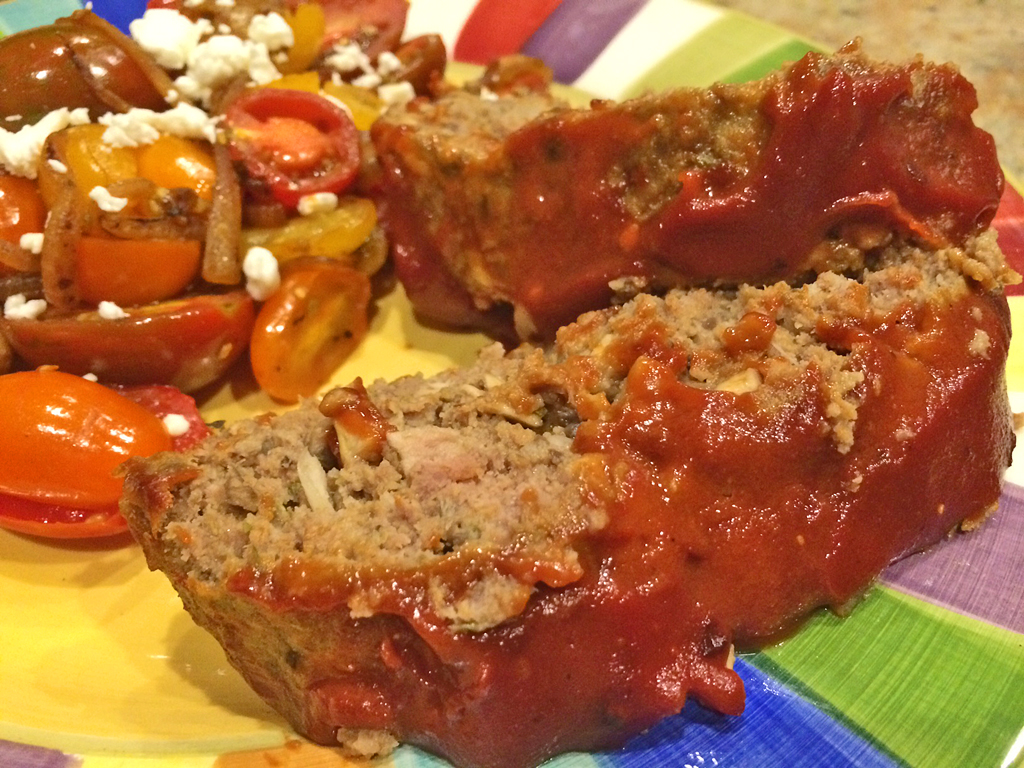 Slices of easy healthy meatloaf with ketchup and tomato salad.