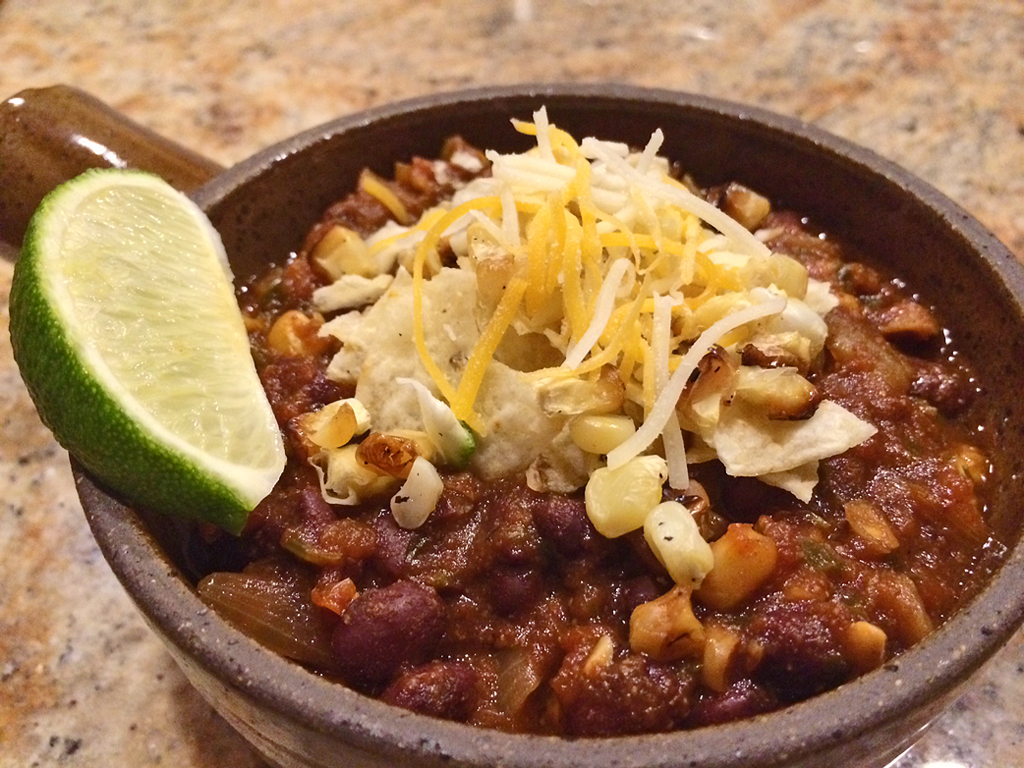 Meatless stew with black beans, salsa, cheese, corn, and a lime.
