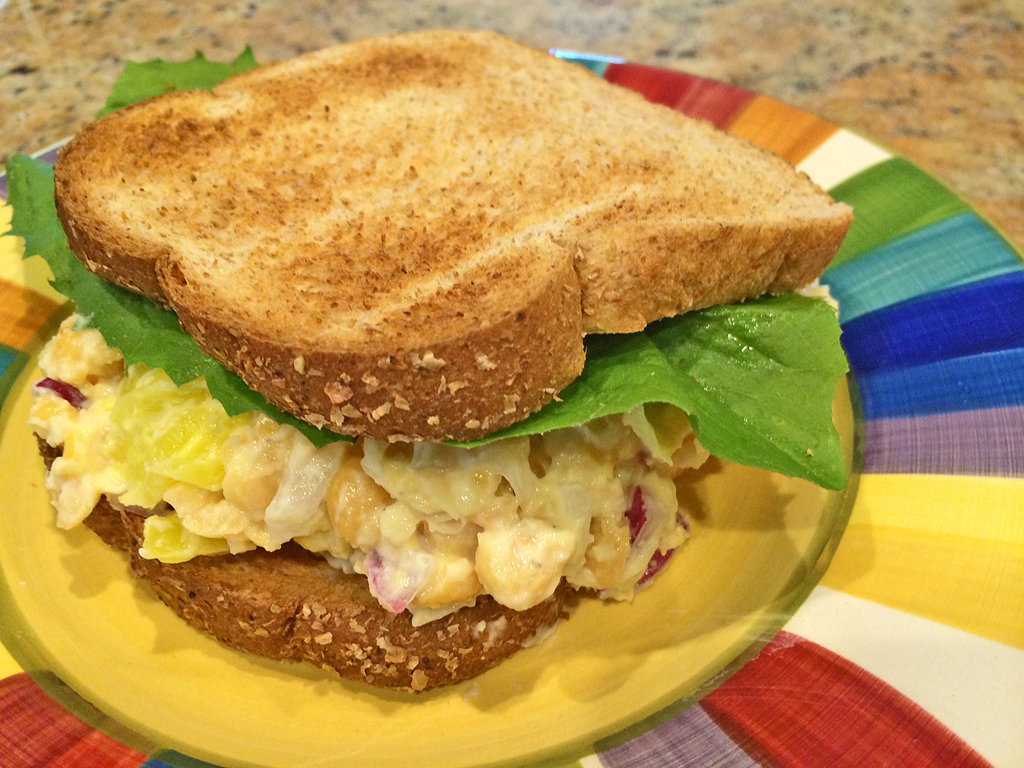 Smashed Chickpea salad on slices of bread with lettuce.