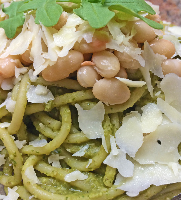 Arugula pesto pasta with white beans and parmesan cheese.